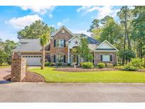 Charming brick home featuring a manicured lawn, two-car garage, and inviting entrance at 1296 Foxtail Dr., Longs, SC 29568