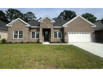 Charming single-story brick home featuring a manicured lawn and attached two-car garage at 297 Waterfall Circle, Little River, SC 29566
