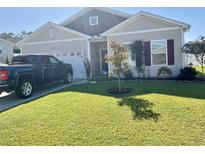 Well-maintained home with a lush green lawn and a dark pickup truck parked in the driveway at 408 Stevia Ct., Conway, SC 29526