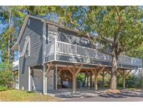Elevated beach home with gray siding, large deck, and partial ocean view at 6001 - 8050 South Kings Hwy., Myrtle Beach, SC 29575