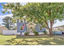 Two-story light blue house with white trim, American flag, and a large tree in the front yard at 4162 Mica Ave., Little River, SC 29566