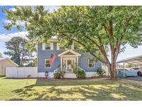 Charming blue two-story home with white trim, landscaped yard and a large shade tree in the front at 4162 Mica Ave., Little River, SC 29566