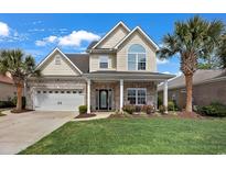 Charming two-story home featuring brick accents, a well-manicured lawn, and a welcoming front porch at 1002 Summers Pl., North Myrtle Beach, SC 29582