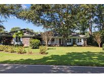 Charming brick home featuring a lush green lawn, mature trees, and inviting front porch at 1562 Hawthorn Dr., Pawleys Island, SC 29585