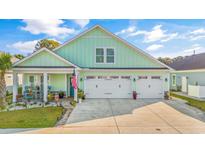 Beautiful light green house with 3-car garage, landscaping, and welcoming porch at 1054 Graybill Lane, North Myrtle Beach, SC 29582