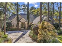 Elegant brick home with a circular driveway and meticulously landscaped front yard, creating a welcoming entrance at 89 Gleneagle Ln., Pawleys Island, SC 29585
