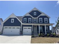 Charming two-story home featuring a three-car garage, large windows, and a welcoming front porch at 7067 Denim Loop, Myrtle Beach, SC 29579
