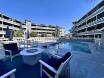 Resort-style condo pool with fire pit and lounge chairs offer a relaxing vacation experience at 1101 Possum Trot Rd. # B302, North Myrtle Beach, SC 29582