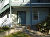 Inviting condo entrance with a blue door, lush greenery, and a well-maintained walkway at 4338 Spa Dr. # 703, Little River, SC 29566