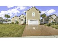 Two-story house with beige exterior, large driveway, and lush green lawn at 217 Southern Breezes Circle, Murrells Inlet, SC 29576