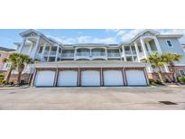 Exterior view of building with garages, balconies, and light green siding at 4879 Dahlia Ct. # 204, Myrtle Beach, SC 29577