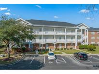 Three story condo building with white balconies, brick accents, and ample parking at 3927 Gladiola Ct. # 204, Myrtle Beach, SC 29588