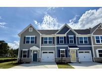 Attractive townhomes with attached garages, various siding colors and stone accents under a partly cloudy sky at 2061 Nw Parow Ln Nw # F, Calabash, NC 28467