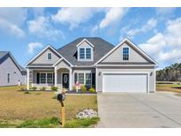 Charming gray home featuring a two-car garage, manicured lawn, and tasteful landscaping, creating an inviting curb appeal at 2327 King Farm Rd., Aynor, SC 29511