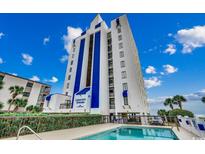 View of the Crescent Towers building with a pool, palms, and blue skies on a sunny day at 2609 S Ocean Blvd. # 403, North Myrtle Beach, SC 29582