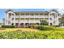 Multi-story condo building with private balconies, white railings, brick accents, and well-maintained landscaping at 703 Riverwalk Dr. # 304, Myrtle Beach, SC 29579