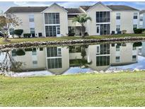 Scenic view of a two-story condo with a pond reflecting the facade and palm tree at 8830 Chandler Dr. # G, Surfside Beach, SC 29575