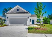 Charming home featuring a grey two-car garage, blue front door, and manicured lawn at 8667 Farrier Dr., Myrtle Beach, SC 29588