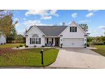 White house with gray roof, two-car garage, and landscaped lawn at 1672 Langley Dr., Longs, SC 29568