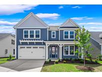 Charming two-story home with blue siding, white trim, a well-manicured lawn, and attached two-car garage at 5036 Cambria Ct., Little River, SC 29566