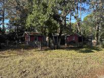 View of a single story brick home with mature trees and a partially fenced yard at 6713 Bryant St., Myrtle Beach, SC 29572