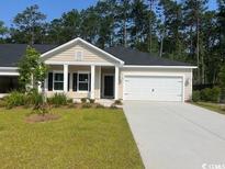 Inviting one-story home featuring a two-car garage, neutral siding, and a well-manicured lawn at 9727 Indigo Creek Blvd., Murrells Inlet, SC 29576