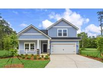 Charming two-story home showcasing a blue shingle exterior, covered porch, and well-manicured front yard at 9746 Indigo Creek Blvd., Murrells Inlet, SC 29576