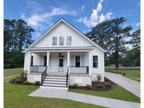 Charming white home with a welcoming front porch, blue shutters and lush landscaping at 805 Comanders Island Rd., Georgetown, SC 29440