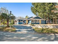 Charming blue house with a well-maintained yard and driveway at 95 Channing Dr., Little River, SC 29566