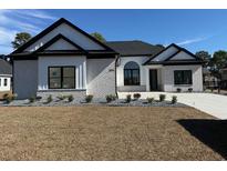 Charming new construction with stylish brickwork, black trim, and beautifully landscaped front yard at 1054 Englemann Oak Dr., Myrtle Beach, SC 29579
