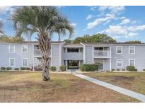 Inviting two-story condo building with light-blue siding and charming balconies, surrounded by well-maintained landscaping at 1356 Glenns Bay Rd. # 207-J, Surfside Beach, SC 29575