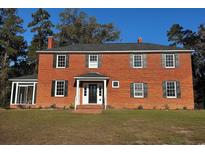 Charming red brick two-story home with black shutters and mature trees at 2110 4Th Ave., Conway, SC 29527