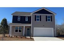 Two-story house with gray and dark gray siding, white garage door, and landscaping at 7303 Meadow Walk Loop, Loris, SC 29569
