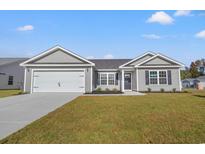 Charming single story home with gray siding, a two-car garage, and beautifully landscaped front yard under a bright blue sky at 354 Barn Owl Way, Conway, SC 29527