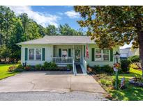 Charming single-story home featuring a cozy porch, green shutters, and well-manicured landscaping at 1305 Conifer Ct., Murrells Inlet, SC 29576