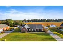 Beautiful brick home featuring an expansive front yard and a charming front porch with rural views at 148 Highmeadow Ln., Aynor, SC 29511