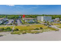 Bright daytime shot of condo building with well-maintained landscaping, parking and beach access at 5601 N Ocean Blvd. # E-316, Myrtle Beach, SC 29577