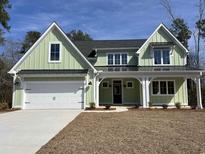 Charming green home featuring a two-car garage, a covered porch, and manicured front yard at 604 Mccown Dr., Conway, SC 29526