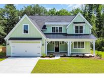 Charming two-story home featuring a covered porch, black metal roof, and attached two-car garage at 604 Mccown Dr., Conway, SC 29526