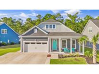 Gray exterior house with teal door, two-car garage, and inviting front porch at 6361 Chadderton Circle, Myrtle Beach, SC 29579