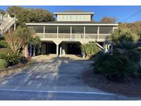 Elevated beach house with covered porch and parking area at 1183 Parker Dr., Pawleys Island, SC 29585