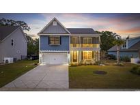 Charming two-story home with a well-manicured lawn, covered porch, and attached garage at 68 Grace Bay Ct., Pawleys Island, SC 29585