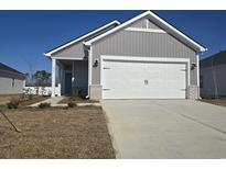 Gray house with white garage door and landscaping at 835 Cypress Preserve Circle, Longs, SC 29568