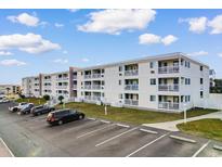 Wide angle view of the condo complex with ample parking and well-maintained landscaping under a partly cloudy sky at 191 Maison Dr. # B320, Myrtle Beach, SC 29572