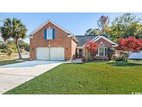 Charming brick home featuring an attached two-car garage, a well-manicured lawn, and an adjacent pond at 305 Duel Ct., Myrtle Beach, SC 29588