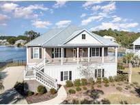 Stunning two-story home boasts double porches and lush landscaping, overlooking a tranquil lakeside view at 76 Eagle Pass Dr., Murrells Inlet, SC 29576