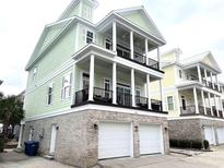 Two-story light green house with white garage doors and a brick base at 305 Shuffleboard Ct., Myrtle Beach, SC 29572