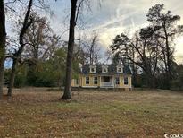 Charming yellow house with white trim and a wrap-around porch at 2708 Main St., Loris, SC 29569