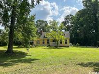 Charming yellow home with a welcoming porch and mature trees in a large, lush yard at 2708 Main St., Loris, SC 29569