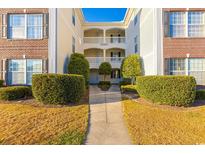 Well-maintained condo complex with manicured landscaping and inviting walkway at 1310 River Oaks Dr. # 2J, Myrtle Beach, SC 29579